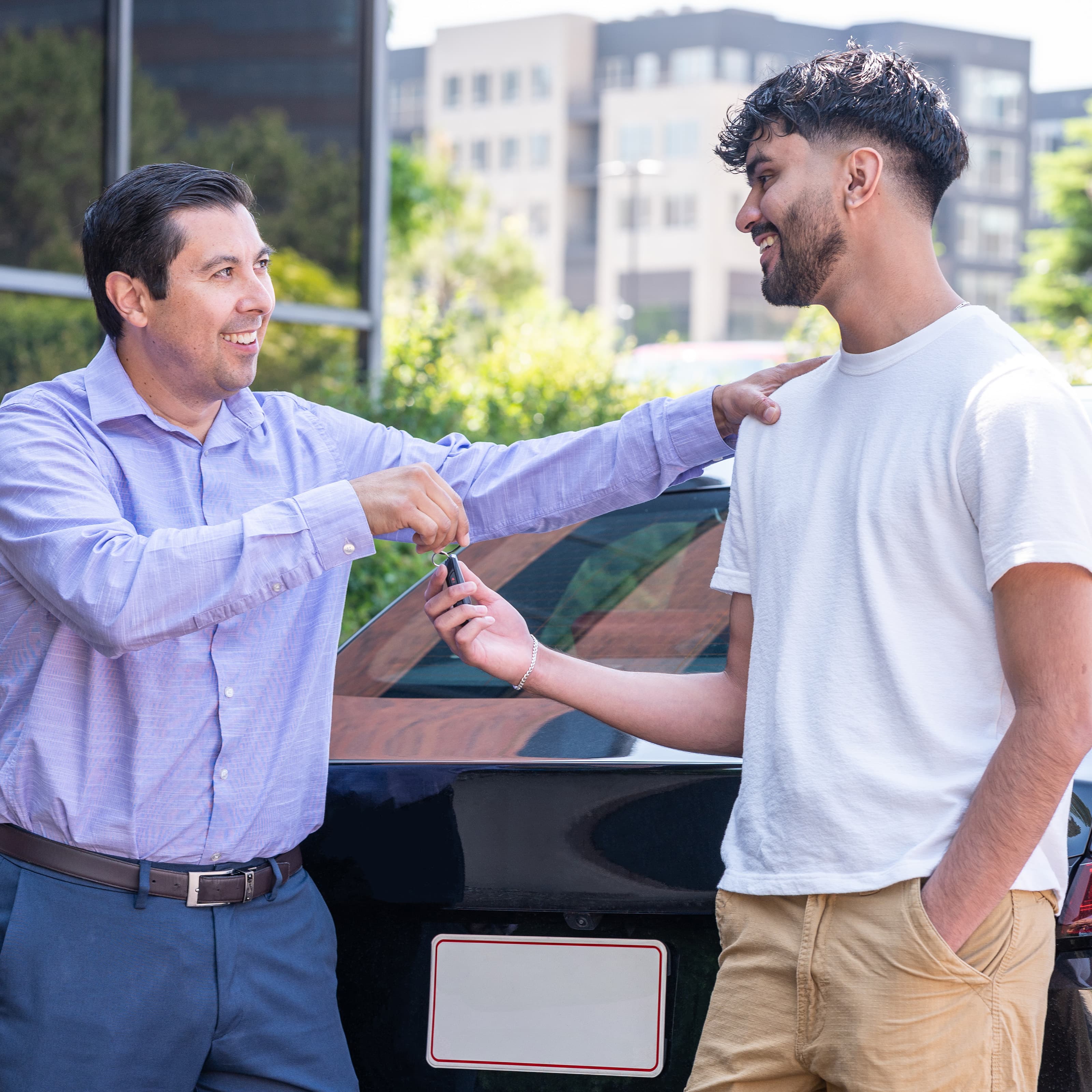 Father and son stnading behind car as father hands over the keys