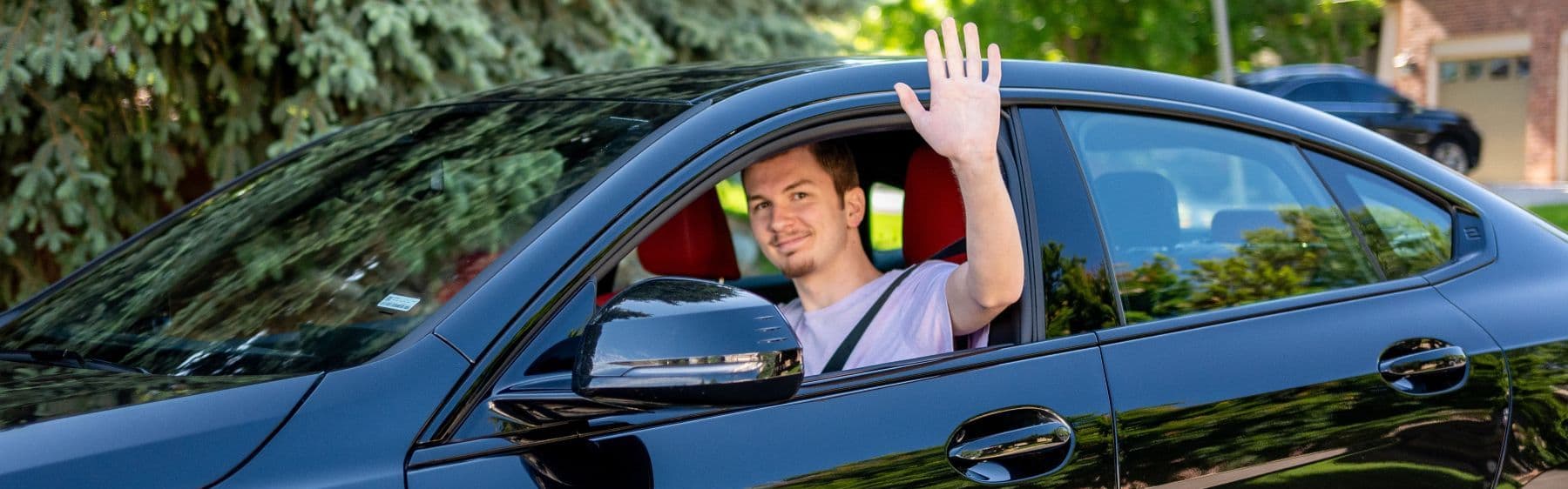Teen driver waving out of car
