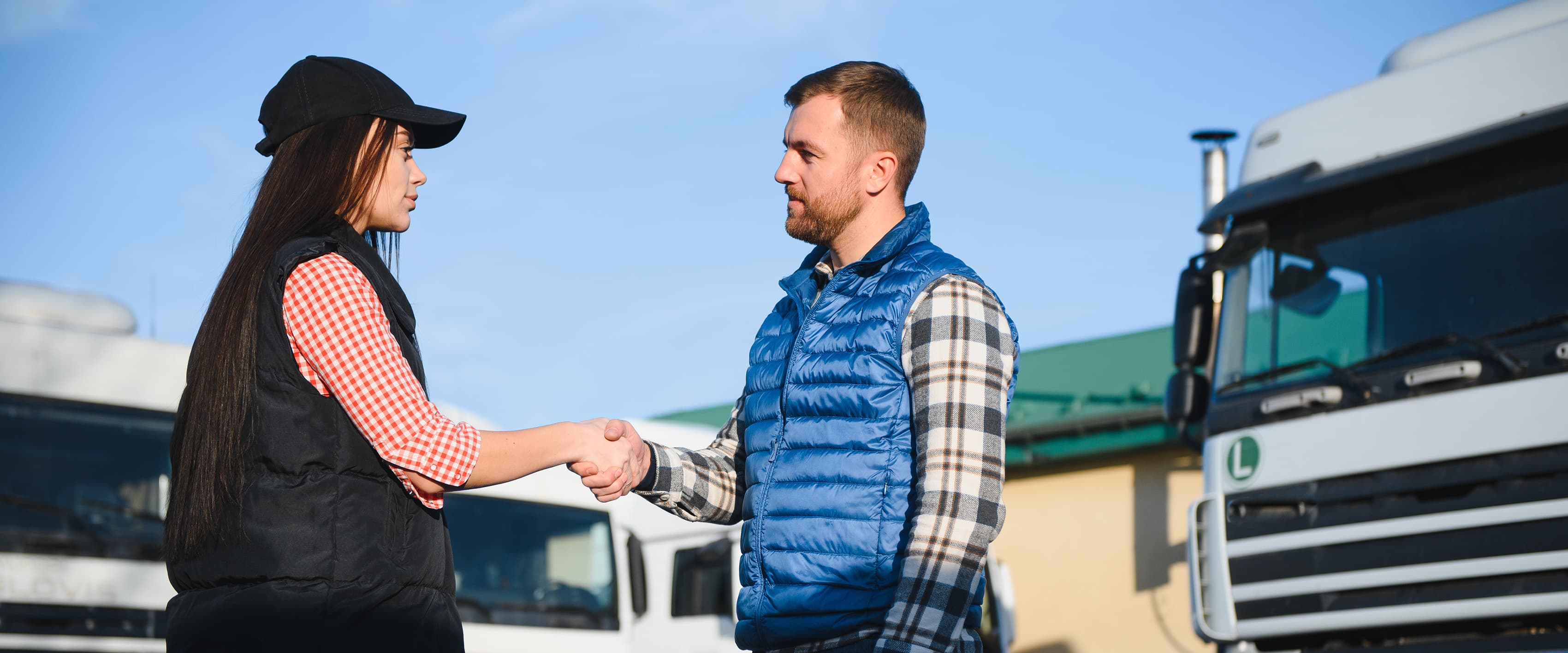 Man and woman shaking hands in front of fleet of vehicles