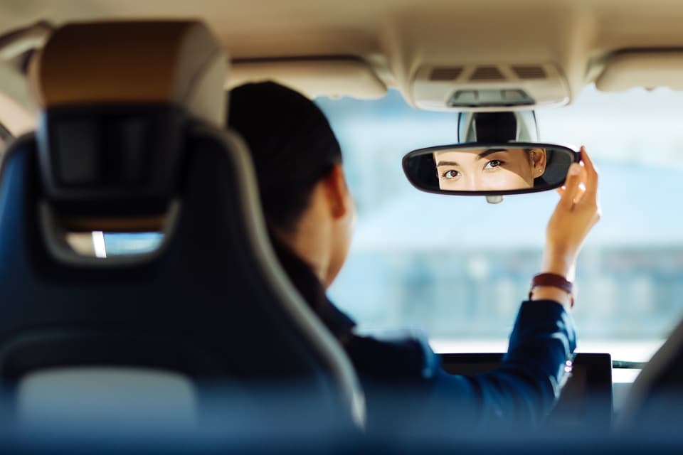 Woman in car adjusting rearview mirror
