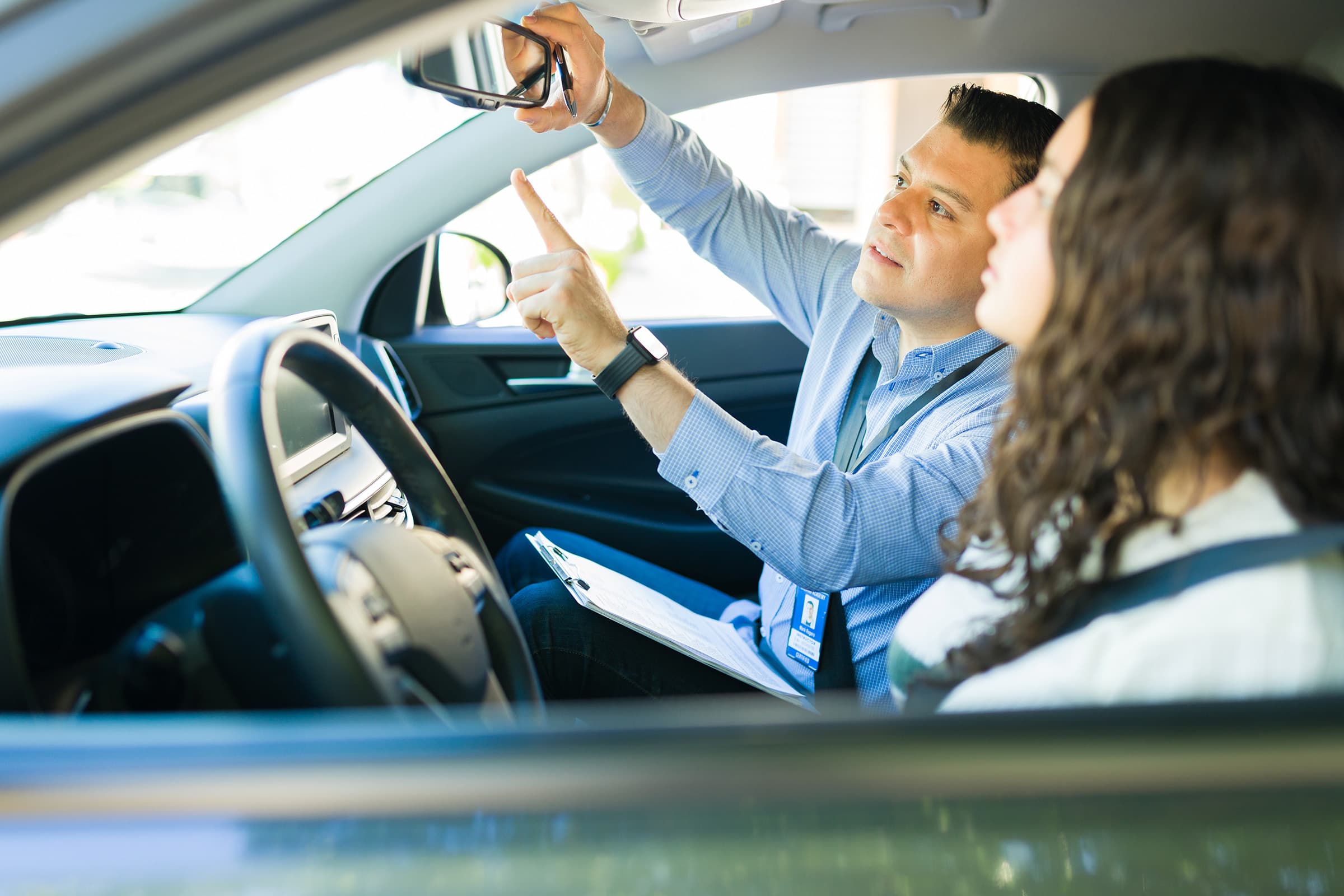 Driving instructor showing student how to adjust mirrors